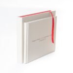 Álbum digital de ecopiel crema con personalización UV y cinta roja, caja de regalo